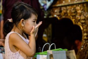 A child drinks the blessed saffron water from the Chenresig empowerment at the KIBI Public Course