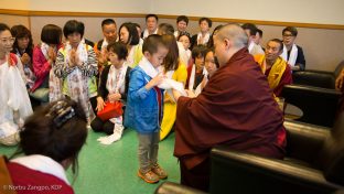 Thaye Dorje, His Holiness the 17th Gyalwa Karmapa, blesses a small child with a katak (ceremonial scarf)