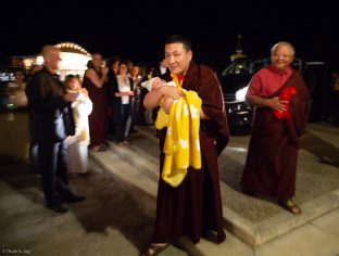 Karmapa cradles Thugsey (his son), with Jigme Rinpoche, Karmapa's General Secretary, smiling in the background