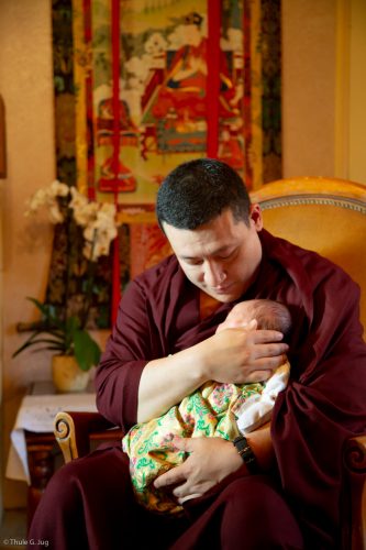 Thaye Dorje, His Holiness the 17th Gyalwa Karmapa, gently cradles Thugsey (his son)